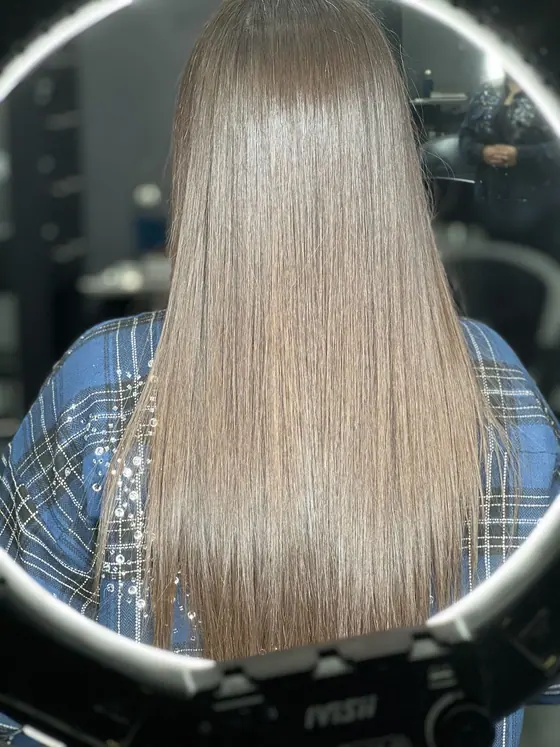 Ash blonde all-over color with a mirror-smooth blow dry, mid-back length