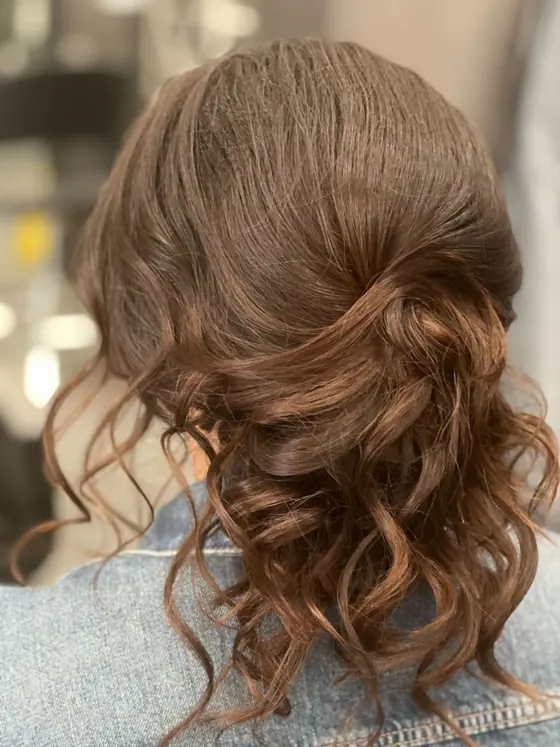 Brunette low updo with hand-shaped curls for a special occasion