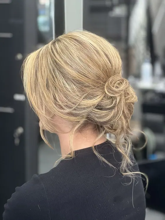 Soft blonde updo with a rolled curl detail